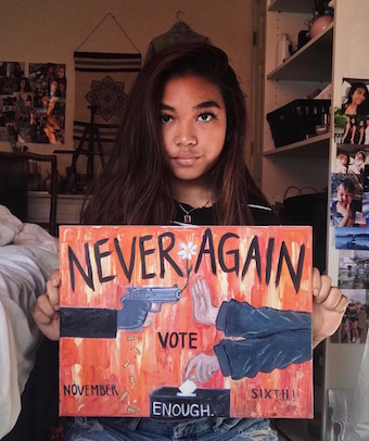 Audrey Hafizian posing with her artwork containing a strong message about gun control. Courtesy of Audrey Hafizians instagram. 